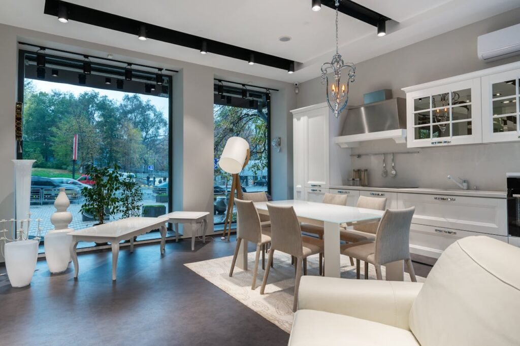 Interior of spacious studio apartment with dining table placed near white kitchen cabinets and soft couch